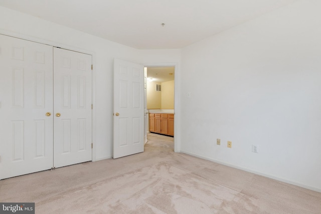 unfurnished bedroom featuring light carpet and a closet