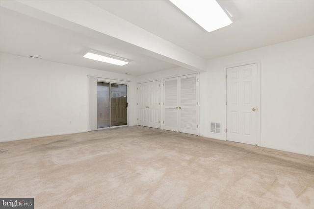 spare room featuring beamed ceiling and light carpet