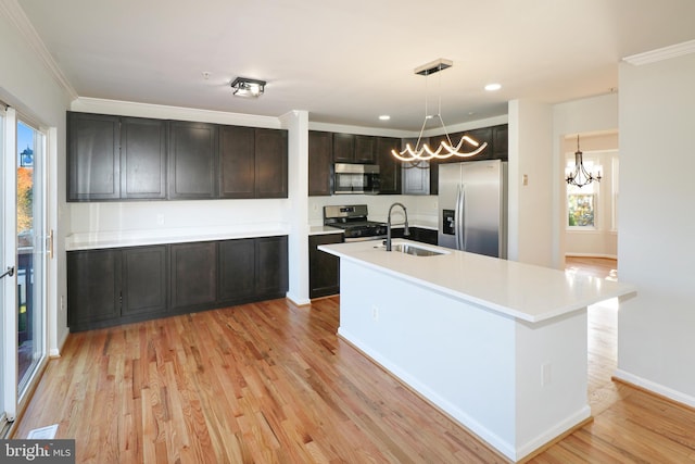 kitchen featuring hanging light fixtures, sink, stainless steel appliances, and light hardwood / wood-style flooring