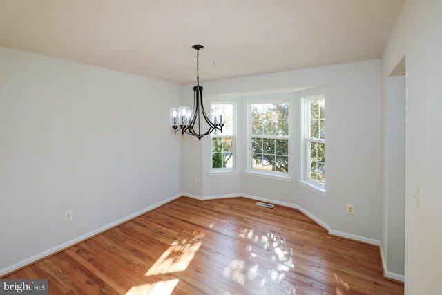 unfurnished dining area featuring wood-type flooring and a chandelier