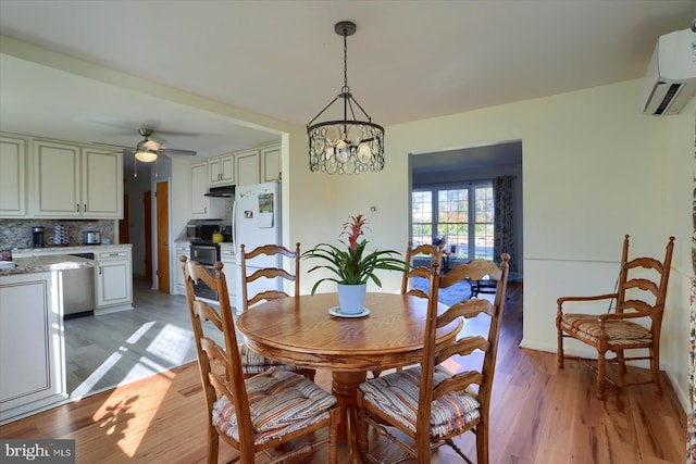 dining room featuring hardwood / wood-style flooring, a wall mounted air conditioner, and ceiling fan with notable chandelier