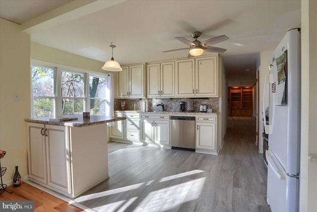 kitchen with hanging light fixtures, white refrigerator, tasteful backsplash, stainless steel dishwasher, and light wood-type flooring