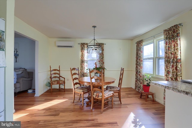 dining space with a wall unit AC and light wood-type flooring