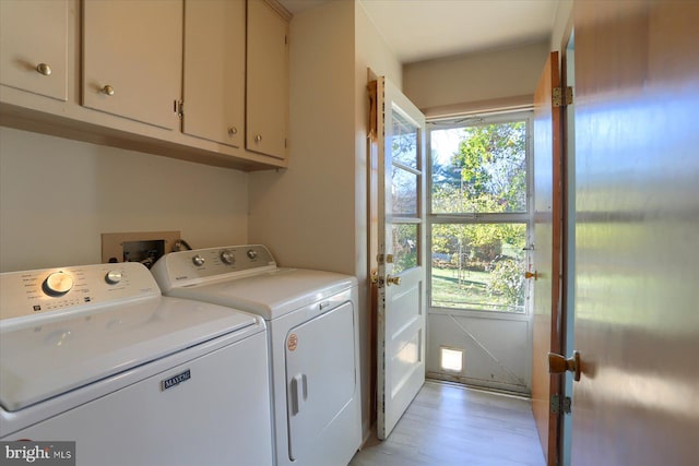 laundry area featuring washer and dryer, light hardwood / wood-style floors, and cabinets