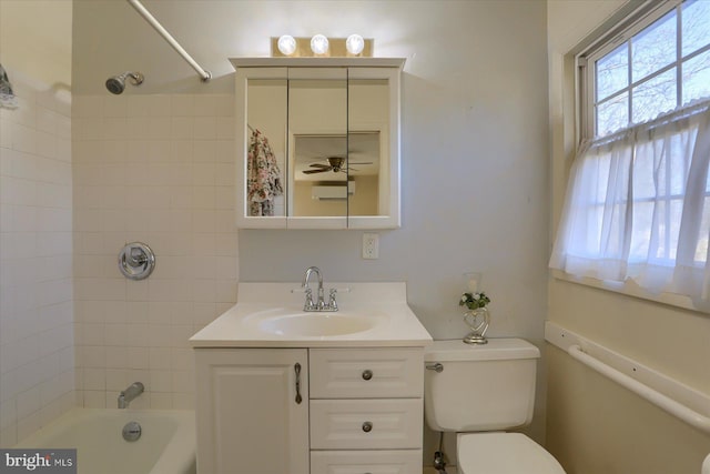 full bathroom with vanity, tiled shower / bath, toilet, and ceiling fan