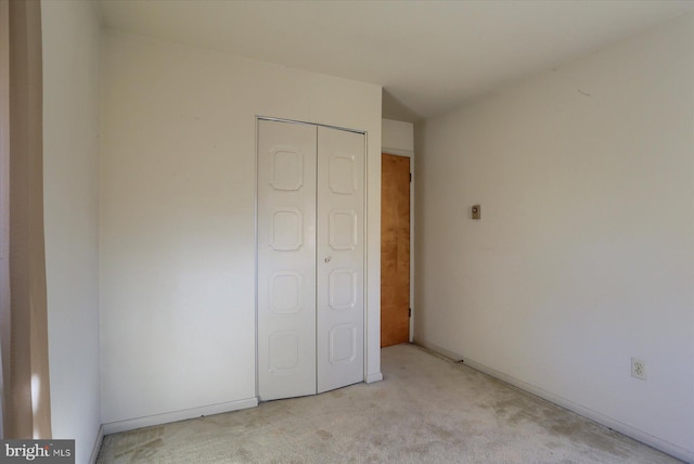 unfurnished bedroom featuring a closet and light carpet