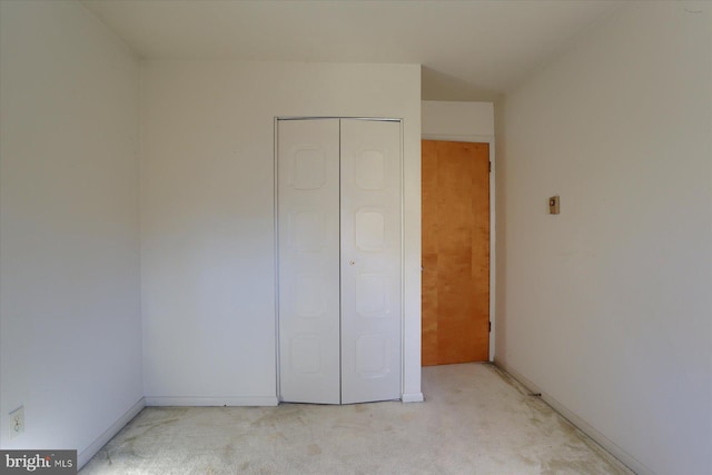 unfurnished bedroom with light carpet and a closet