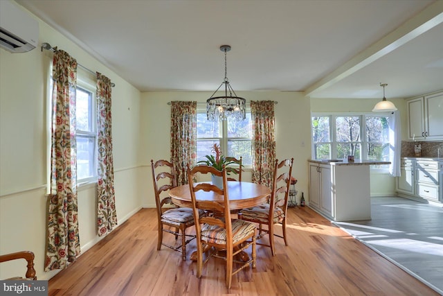 dining area featuring an inviting chandelier, light hardwood / wood-style flooring, and an AC wall unit