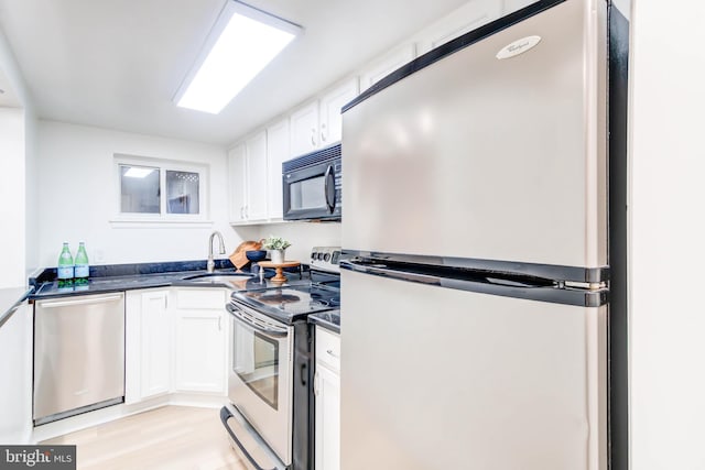 kitchen featuring white cabinetry, sink, light wood-type flooring, and appliances with stainless steel finishes