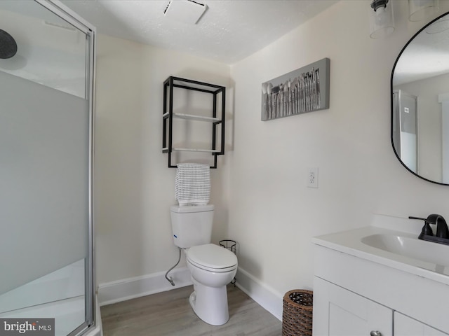 bathroom featuring a shower with door, hardwood / wood-style floors, vanity, and toilet