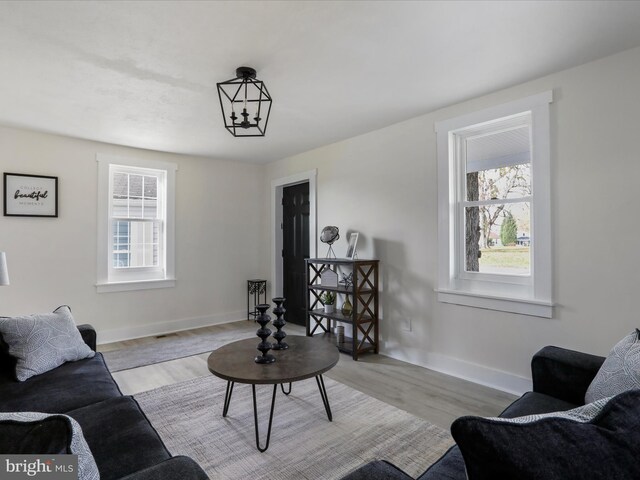 living room featuring light hardwood / wood-style floors, a wealth of natural light, and a notable chandelier