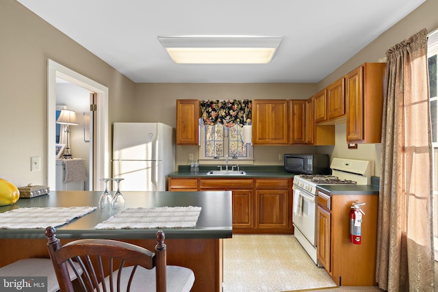 kitchen with white appliances, sink, and a breakfast bar area