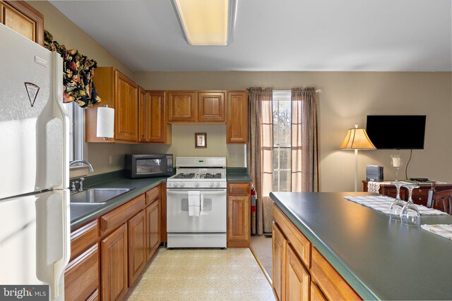 1324 River Rd, New Hope, PA 18938 - kitchen featuring white appliances, a sink, dark countertops, light flooring, and brown cabinetry
