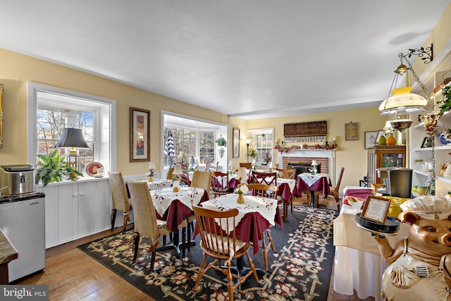 dining space featuring hardwood / wood-style flooring and a brick fireplace