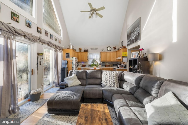 living room with ceiling fan, high vaulted ceiling, and light wood-type flooring