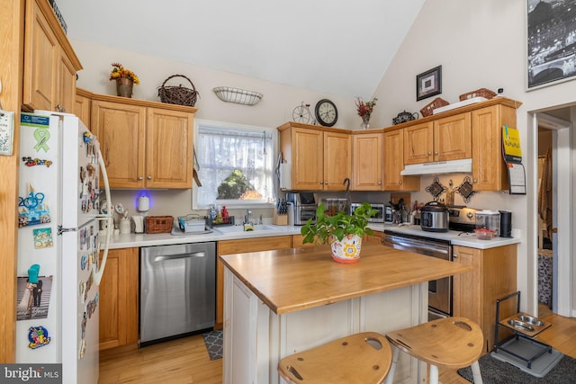 kitchen with a kitchen breakfast bar, lofted ceiling, stainless steel appliances, and light hardwood / wood-style flooring