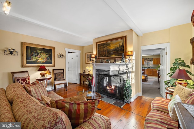 living room with beam ceiling, a premium fireplace, and light hardwood / wood-style flooring