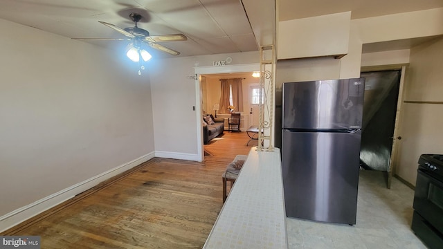 kitchen featuring stainless steel refrigerator, white cabinetry, ceiling fan, black electric range, and light hardwood / wood-style flooring