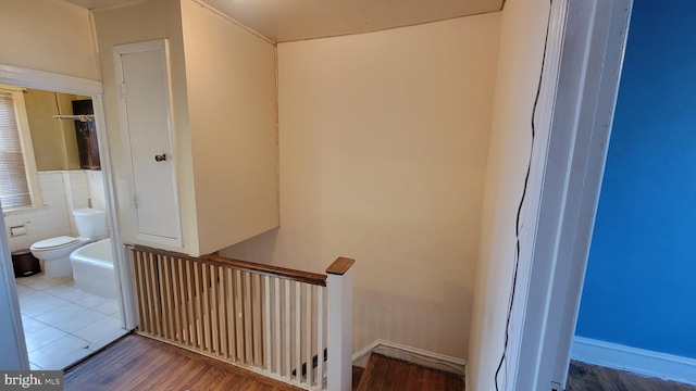 staircase featuring hardwood / wood-style floors and tile walls