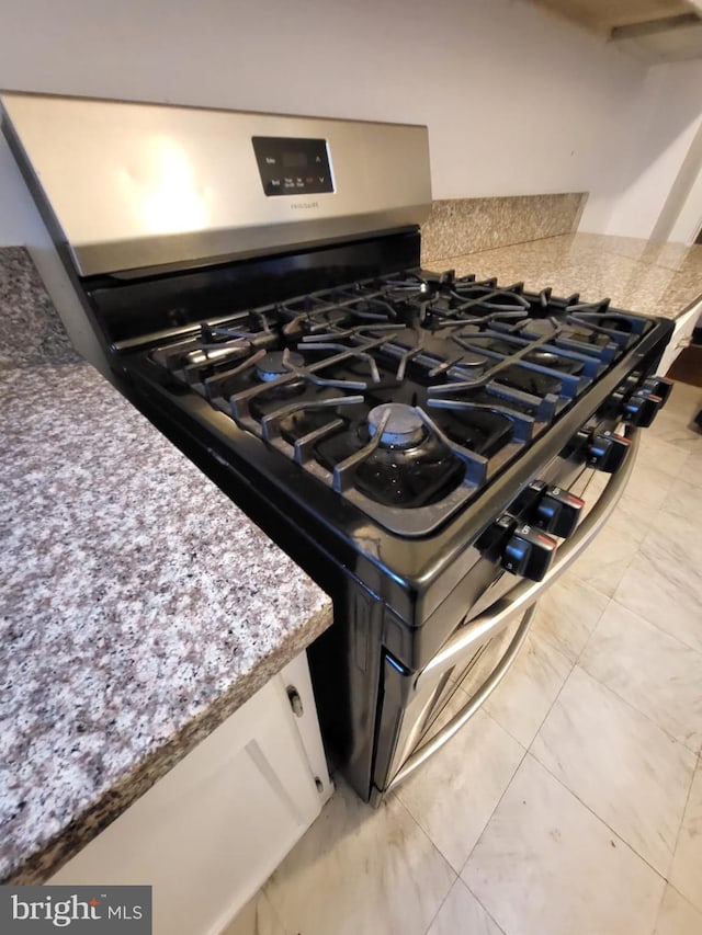 details featuring stainless steel gas range oven and white cabinetry