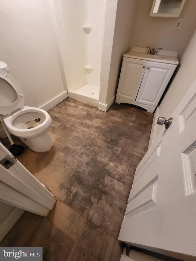 bathroom featuring hardwood / wood-style floors, vanity, toilet, and a shower