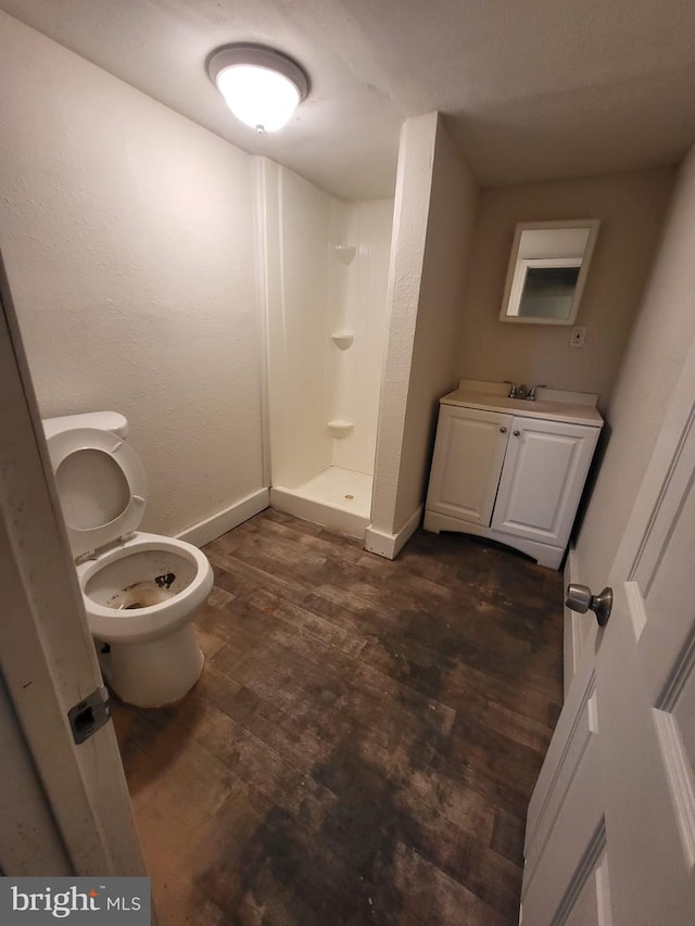 bathroom featuring toilet, a shower, vanity, and hardwood / wood-style floors