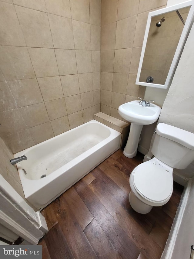 bathroom with hardwood / wood-style flooring, toilet, and tiled shower