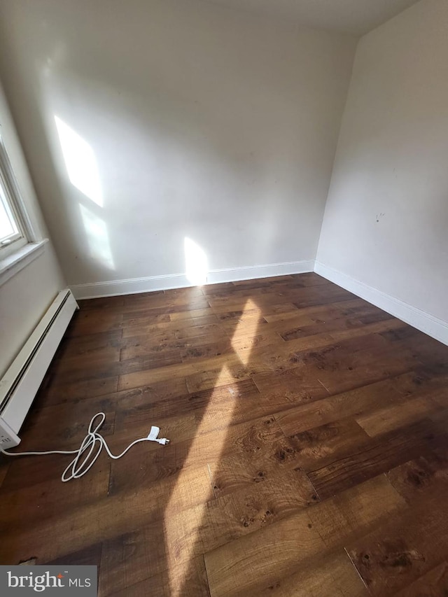 empty room featuring dark wood-type flooring and baseboard heating