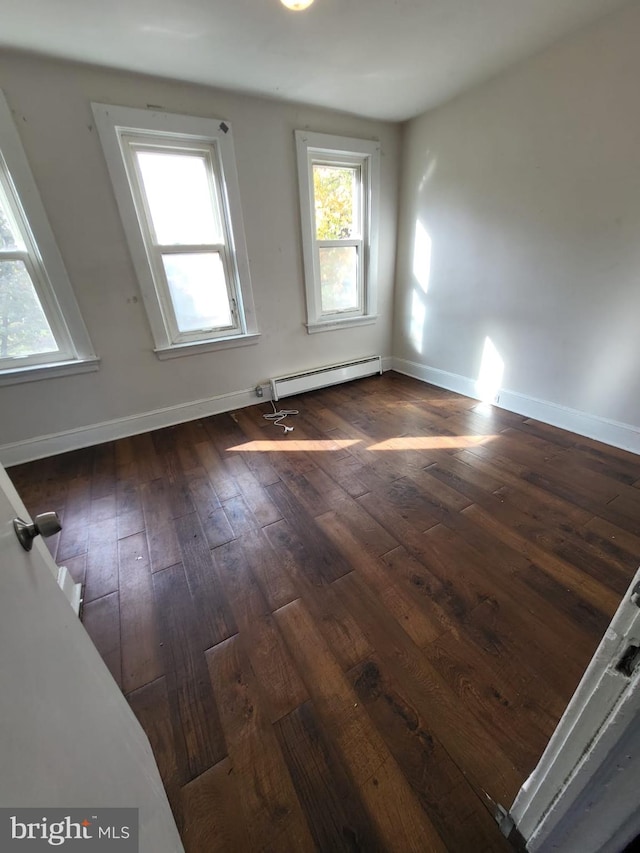 spare room featuring dark wood-type flooring and baseboard heating