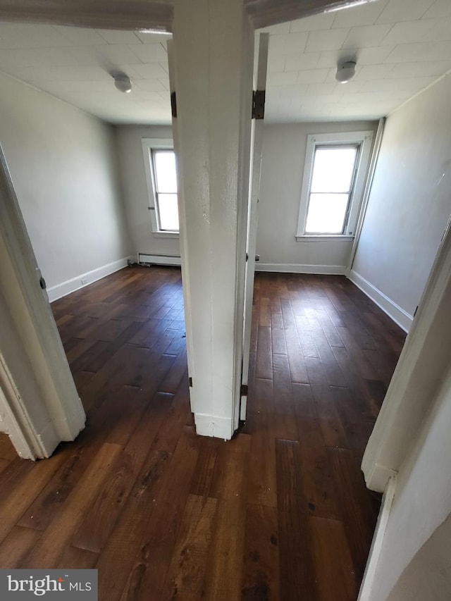 corridor with dark wood-type flooring, plenty of natural light, and a baseboard radiator