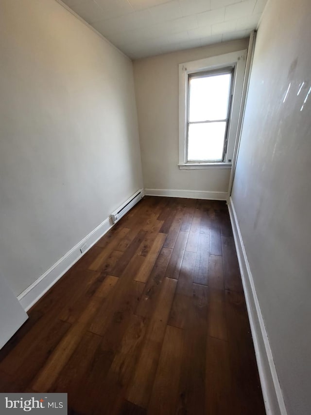 unfurnished room featuring dark wood-type flooring and a baseboard heating unit