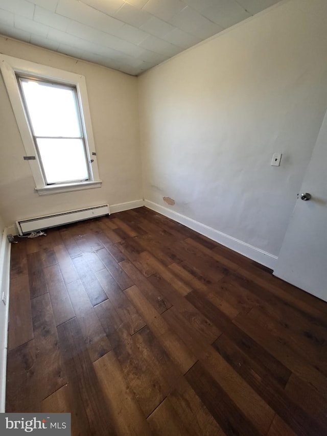 unfurnished room with dark hardwood / wood-style floors and a baseboard radiator