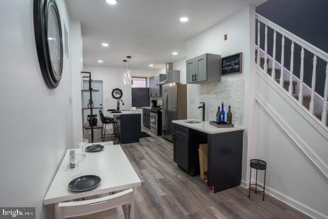 kitchen featuring sink, tasteful backsplash, dark hardwood / wood-style flooring, stainless steel fridge, and pendant lighting