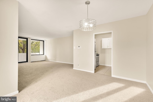 carpeted spare room featuring an inviting chandelier