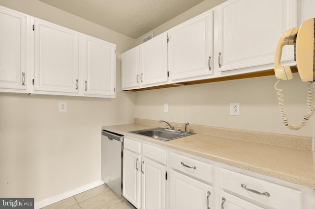 kitchen with a textured ceiling, sink, light tile patterned floors, stainless steel dishwasher, and white cabinetry