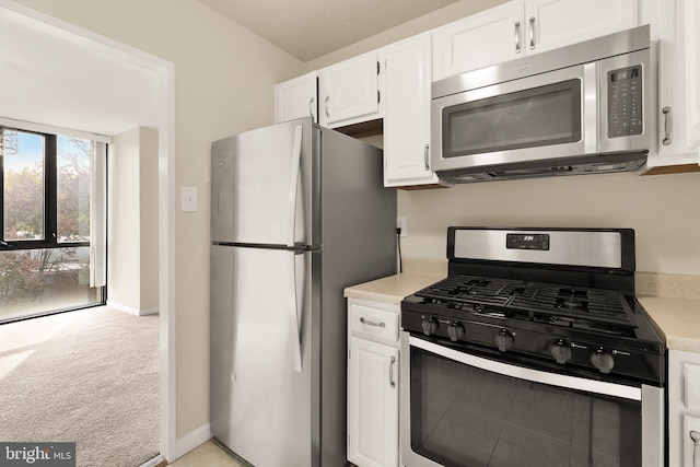 kitchen with white cabinetry, appliances with stainless steel finishes, and light colored carpet