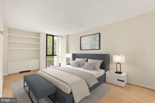 bedroom featuring light hardwood / wood-style flooring and a textured ceiling