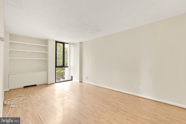 empty room featuring a textured ceiling and light hardwood / wood-style flooring