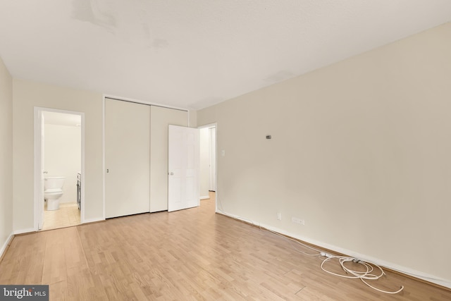 unfurnished bedroom with light hardwood / wood-style floors, ensuite bath, and a closet