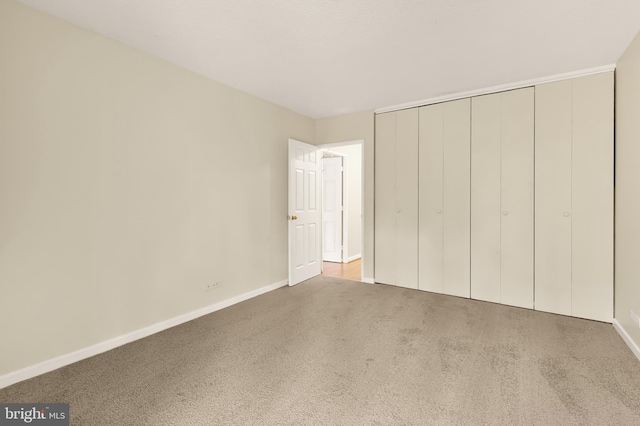 unfurnished bedroom featuring light colored carpet and a closet