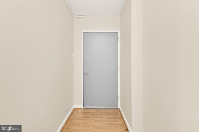 corridor featuring light hardwood / wood-style floors and a textured ceiling