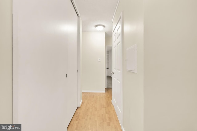 hall with a textured ceiling and light wood-type flooring