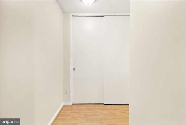 hallway featuring a textured ceiling and light hardwood / wood-style flooring