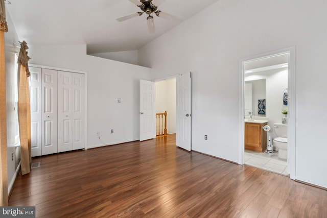 unfurnished bedroom with hardwood / wood-style flooring, ceiling fan, ensuite bath, and high vaulted ceiling