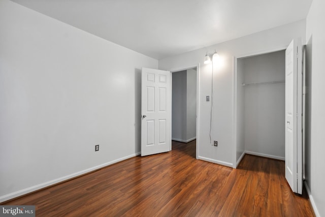 unfurnished bedroom featuring dark wood-type flooring and a closet