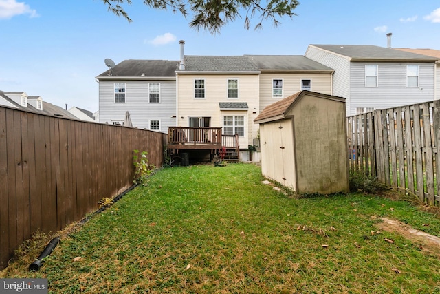 back of property featuring a wooden deck, a lawn, and a shed