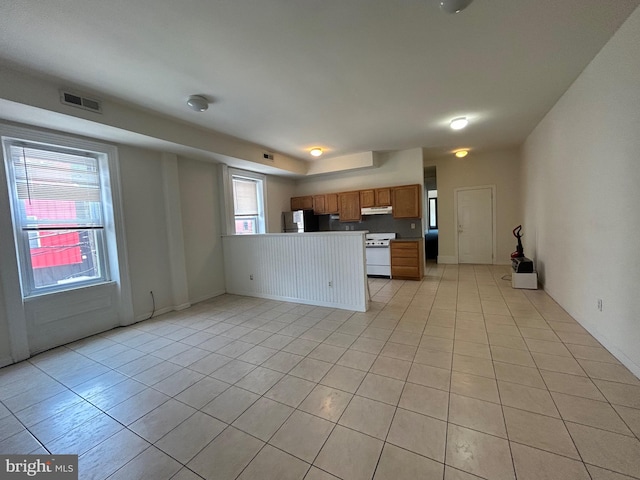 kitchen featuring light tile patterned flooring, stainless steel refrigerator, and white range oven