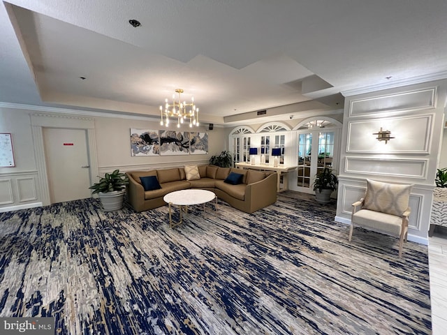 living room with a raised ceiling, crown molding, and a chandelier