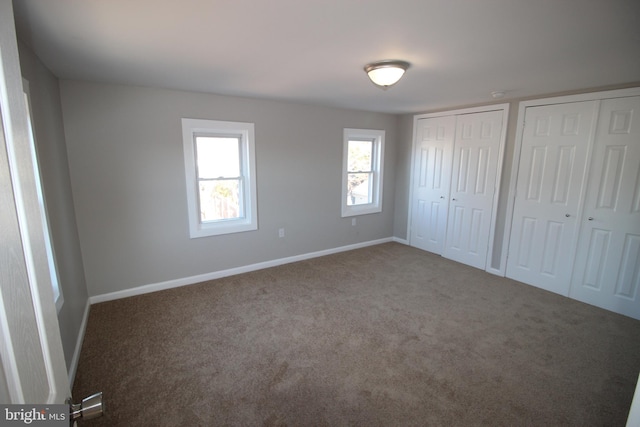 unfurnished bedroom with carpet and two closets