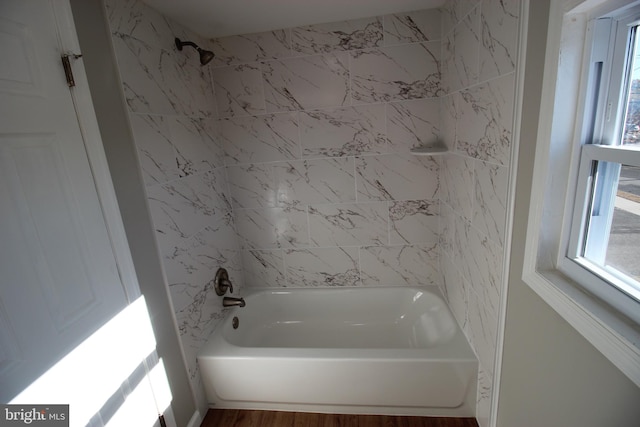 bathroom with hardwood / wood-style flooring and tiled shower / bath